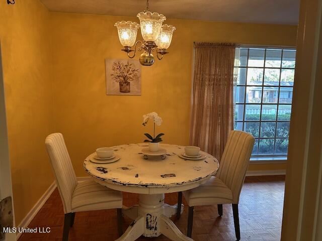 dining room with dark parquet flooring and a chandelier