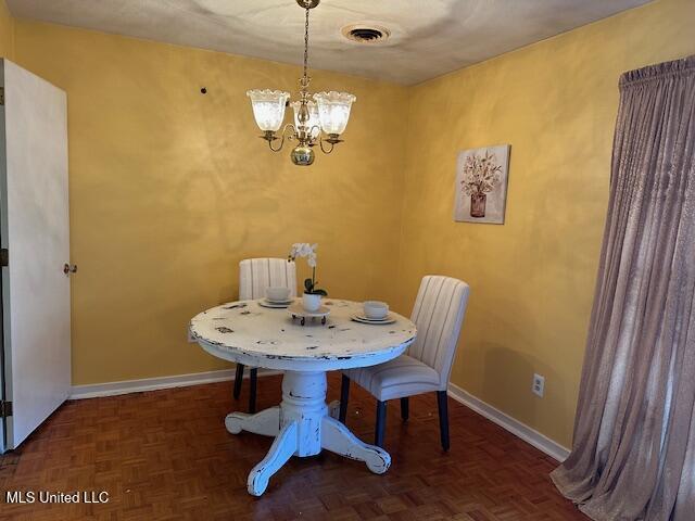 dining room with dark parquet floors and an inviting chandelier