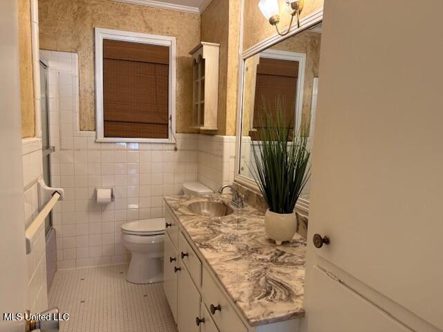 bathroom with vanity, crown molding, tile walls, tile patterned flooring, and toilet