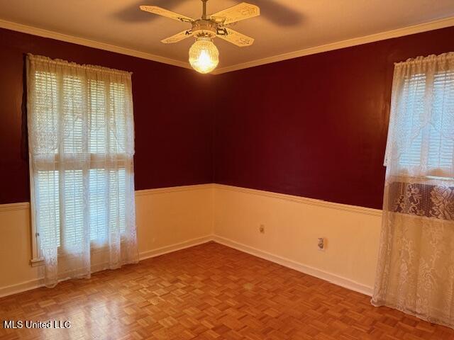 empty room with ceiling fan, crown molding, and parquet floors