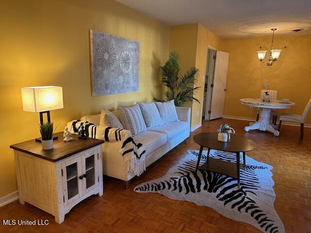 living room featuring dark parquet flooring and a chandelier