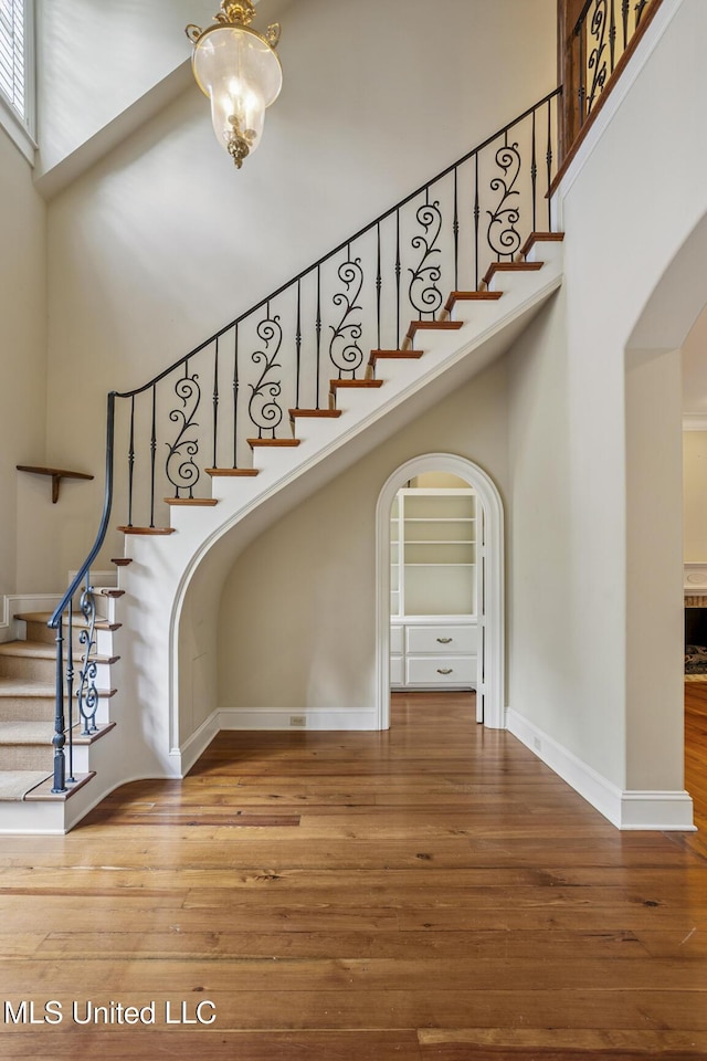 1 Cypress Ln, Jackson, MS 39211 - stairs featuring a high ceiling, arched walkways, wood finished floors, and a chandelier