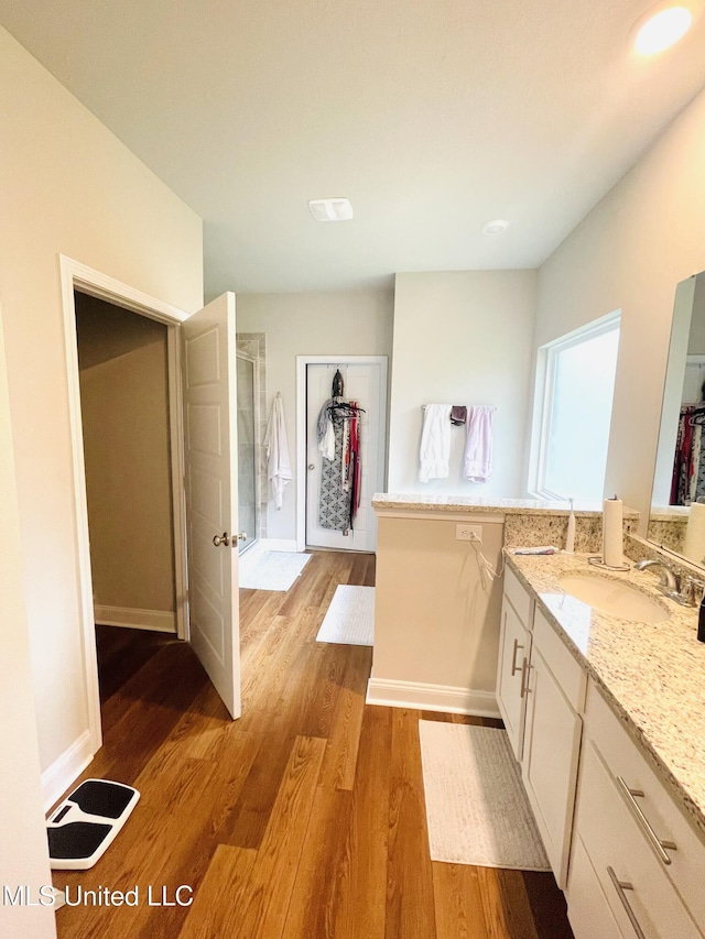 bathroom with baseboards, wood finished floors, vanity, and a stall shower