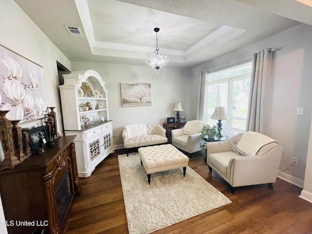 living area with dark wood finished floors, crown molding, and a tray ceiling