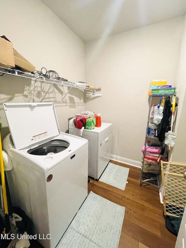 laundry room featuring baseboards, wood finished floors, washer and dryer, and laundry area