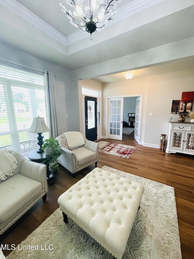 living area featuring baseboards, wood finished floors, an inviting chandelier, and ornamental molding