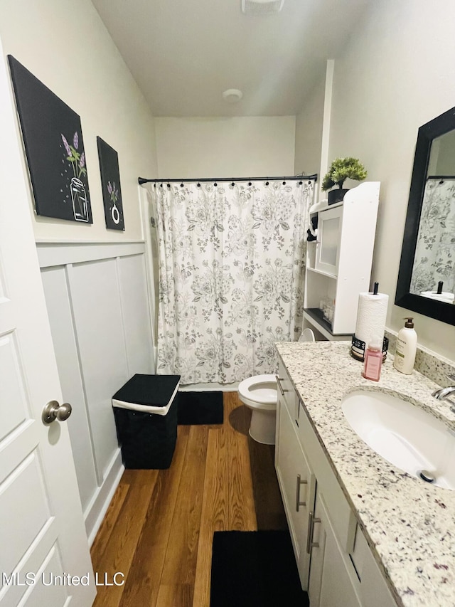 bathroom featuring curtained shower, wood finished floors, toilet, and vanity