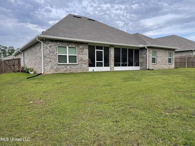 rear view of house with a fenced backyard, a sunroom, a yard, and brick siding
