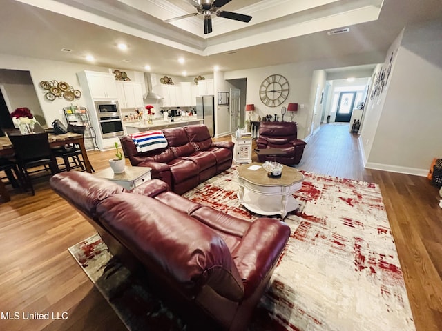 living area featuring light wood-style flooring, visible vents, recessed lighting, a ceiling fan, and a raised ceiling