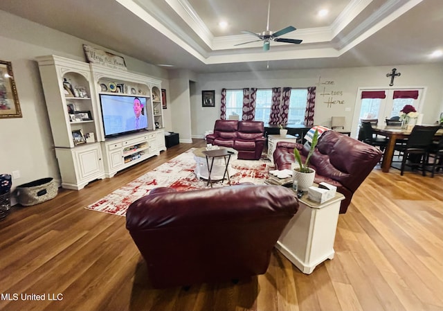 living room featuring recessed lighting, a raised ceiling, a ceiling fan, ornamental molding, and light wood-style floors