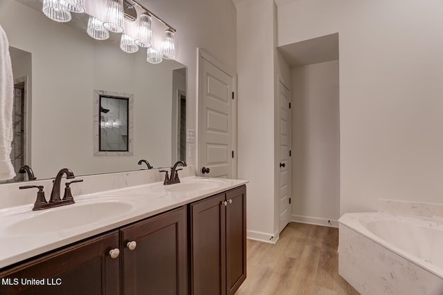 2561 Dela Dr, Southaven, MS 38672 - full bathroom with double vanity, a bath, wood finished floors, and baseboards