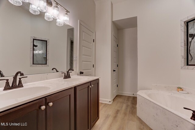 2561 Dela Dr, Southaven, MS 38672 - bathroom with a garden tub, double vanity, wood finished floors, and baseboards