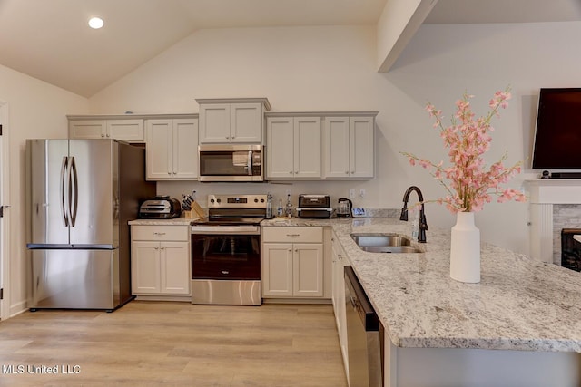 2561 Dela Dr, Southaven, MS 38672 - kitchen featuring appliances with stainless steel finishes, a sink, a peninsula, vaulted ceiling, and light stone countertops