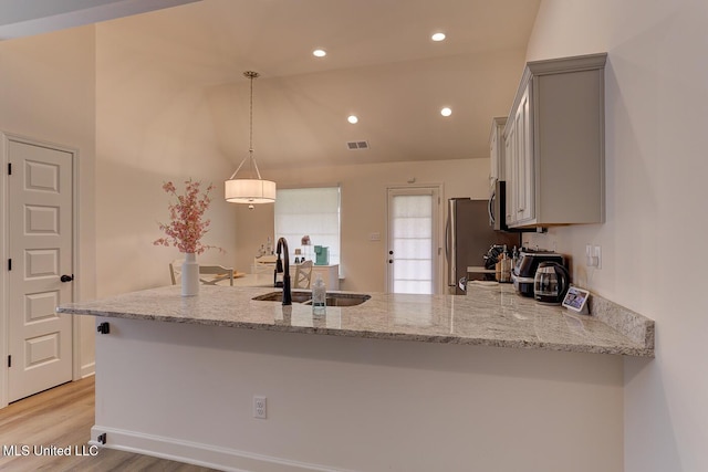 2561 Dela Dr, Southaven, MS 38672 - kitchen with a sink, a peninsula, appliances with stainless steel finishes, light stone countertops, and vaulted ceiling