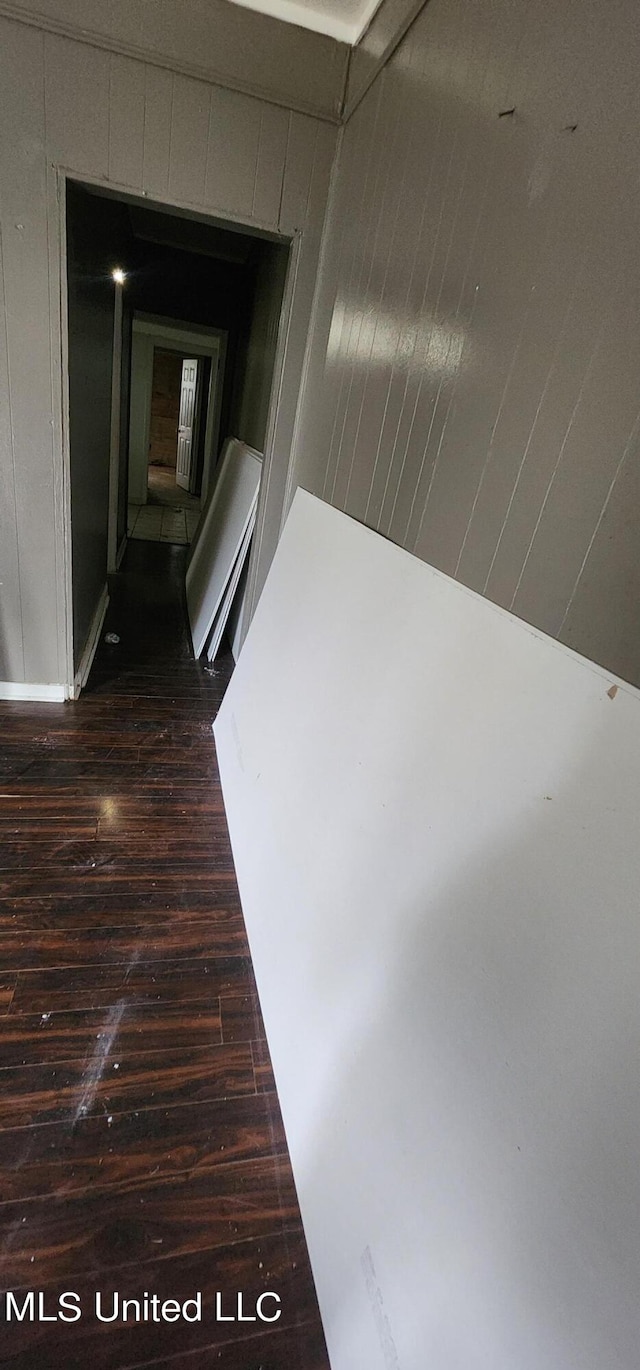 corridor featuring wooden walls and dark hardwood / wood-style flooring