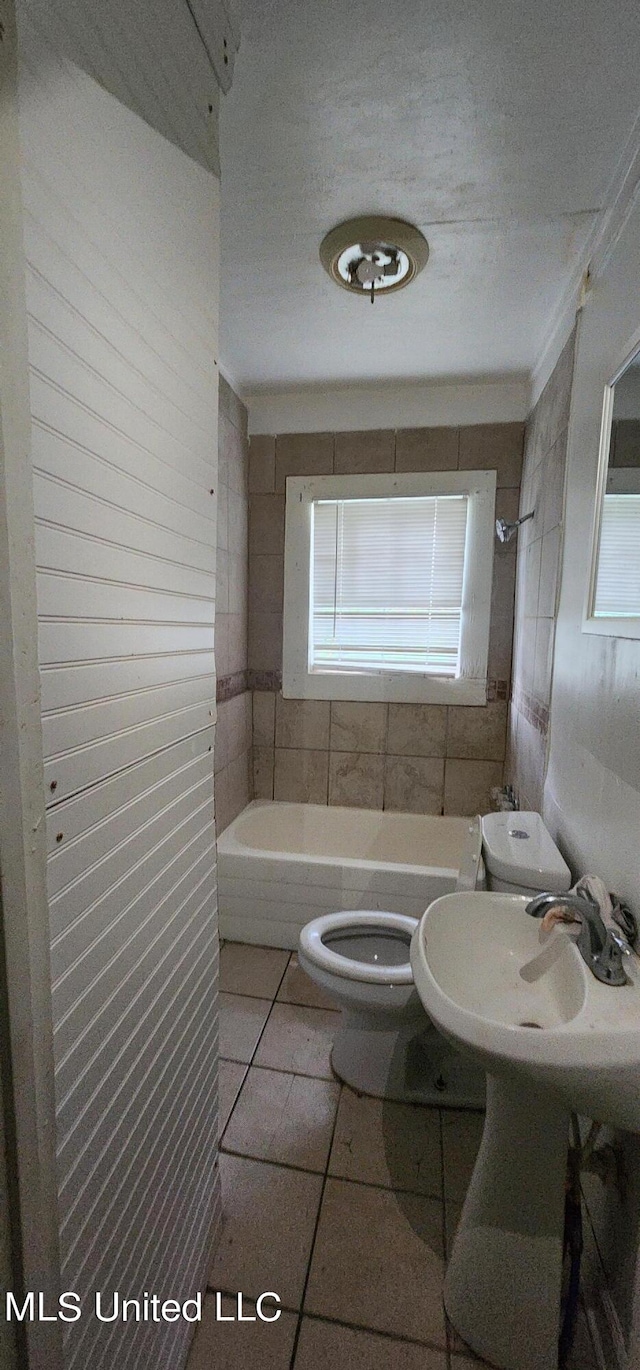 full bathroom with toilet, tiled shower / bath combo, sink, and tile patterned flooring