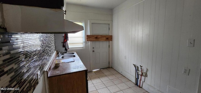 kitchen featuring extractor fan, wooden walls, sink, and light tile patterned floors