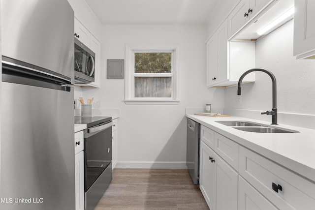 kitchen with stainless steel appliances, white cabinets, light countertops, and a sink