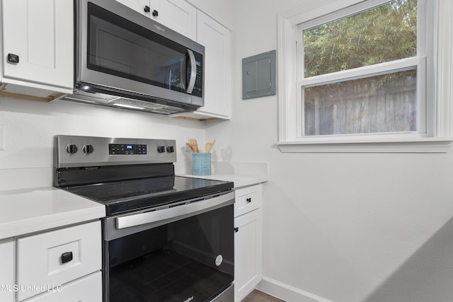 kitchen with white cabinetry, baseboards, light countertops, appliances with stainless steel finishes, and electric panel