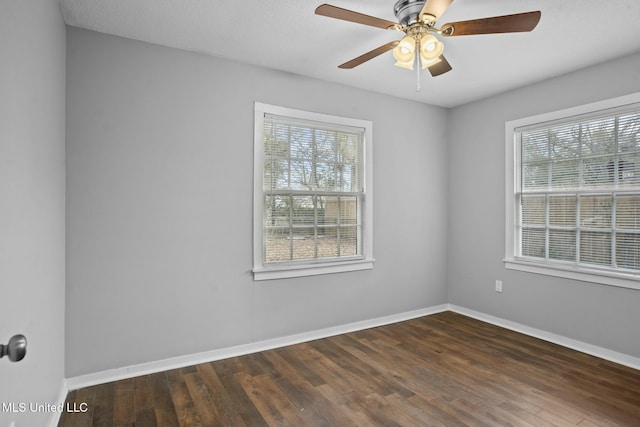 spare room featuring ceiling fan, dark wood-type flooring, and plenty of natural light