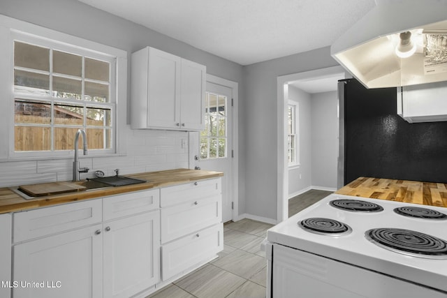 kitchen with white cabinets, wooden counters, decorative backsplash, and stainless steel refrigerator