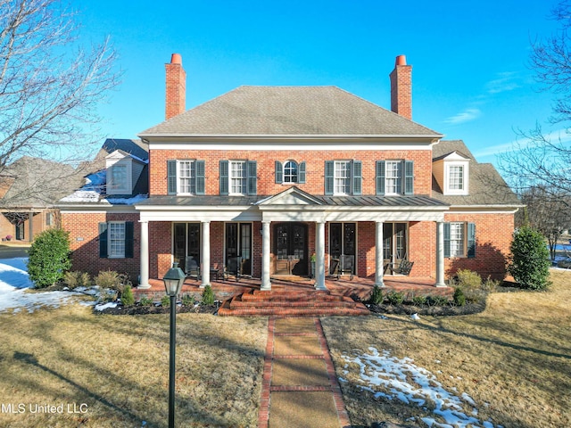 colonial inspired home featuring a porch and a front yard