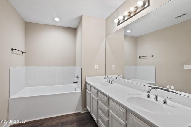 bathroom with a bath, vanity, and wood-type flooring