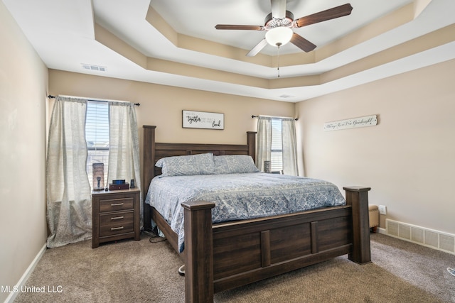 bedroom featuring light carpet, ceiling fan, a raised ceiling, and multiple windows