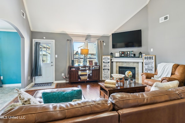 living room featuring vaulted ceiling, dark hardwood / wood-style flooring, crown molding, and a fireplace