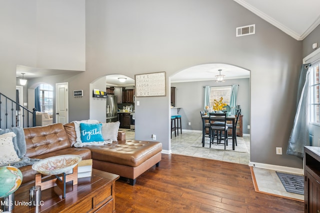 living room featuring high vaulted ceiling, plenty of natural light, hardwood / wood-style floors, and ornamental molding