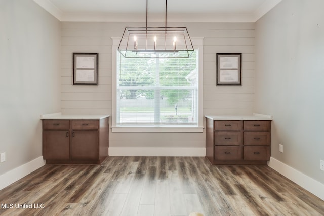 unfurnished dining area with baseboards, wood finished floors, and a chandelier