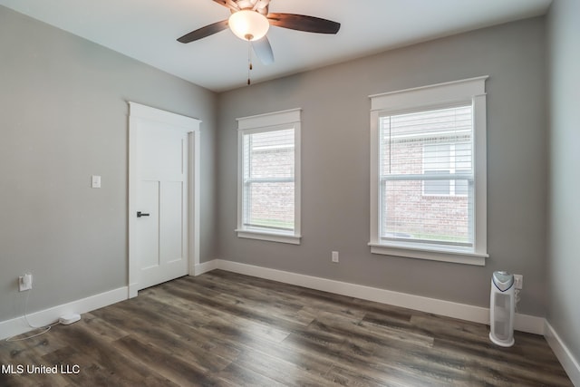 spare room featuring a ceiling fan, dark wood-style flooring, and baseboards