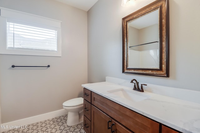 bathroom featuring toilet, vanity, and baseboards