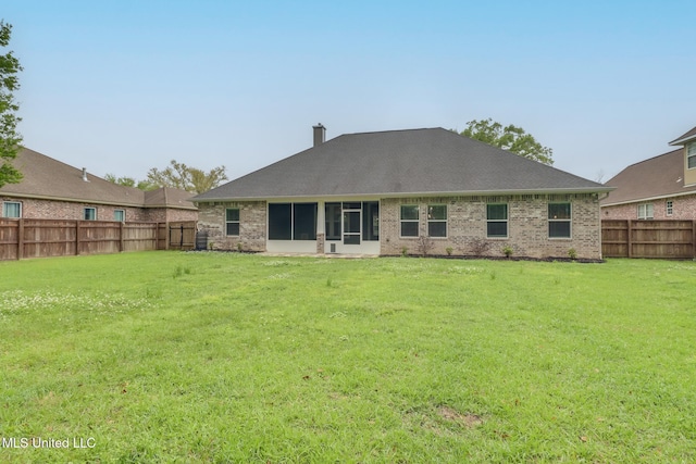 rear view of house with a fenced backyard, a shingled roof, brick siding, and a yard