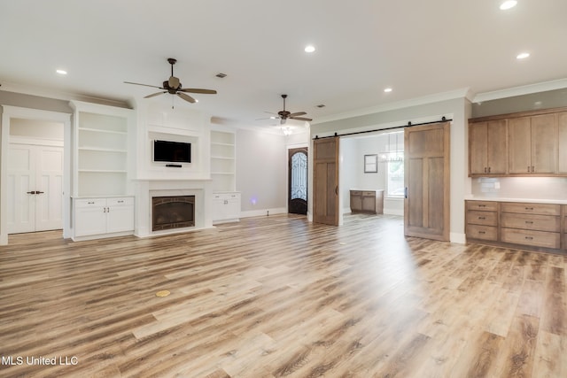 unfurnished living room with crown molding, recessed lighting, a barn door, light wood finished floors, and ceiling fan