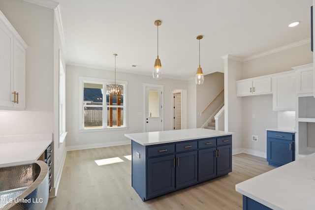 kitchen with white cabinets, blue cabinets, hanging light fixtures, and light wood-type flooring