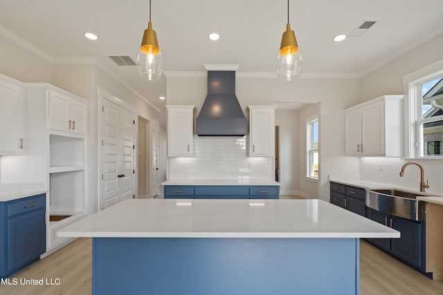 kitchen featuring custom range hood, blue cabinetry, and white cabinets