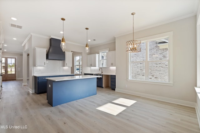 kitchen with decorative light fixtures, light wood-type flooring, blue cabinetry, custom exhaust hood, and white cabinets