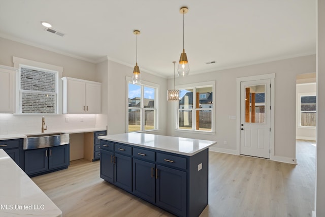 kitchen featuring hanging light fixtures, sink, blue cabinets, white cabinetry, and light hardwood / wood-style floors