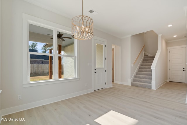 unfurnished dining area featuring crown molding, ceiling fan with notable chandelier, and light hardwood / wood-style floors