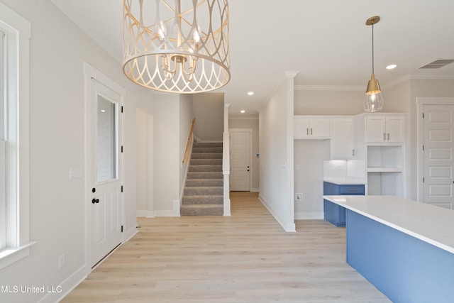 kitchen featuring white cabinets, light hardwood / wood-style flooring, ornamental molding, a notable chandelier, and decorative light fixtures