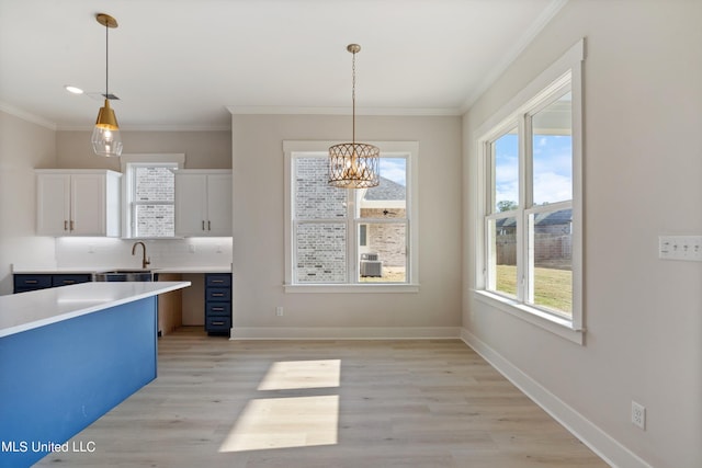 kitchen with light hardwood / wood-style floors, white cabinets, tasteful backsplash, and hanging light fixtures