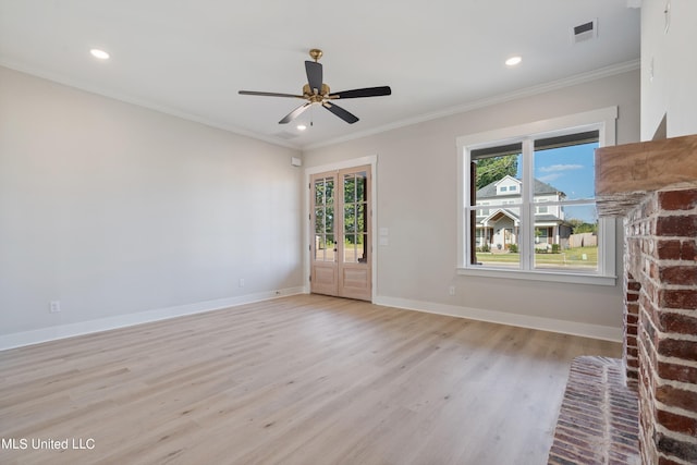 empty room with light hardwood / wood-style floors, ornamental molding, a brick fireplace, and ceiling fan