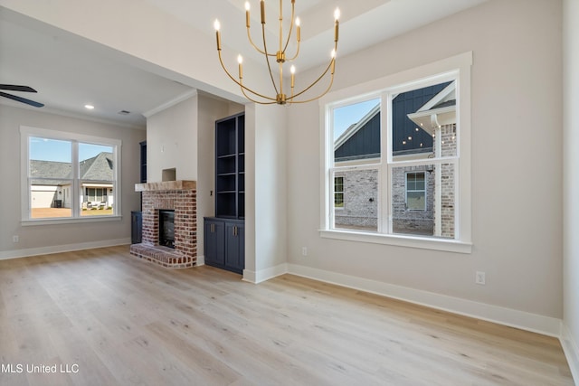 unfurnished living room featuring ornamental molding, light hardwood / wood-style flooring, a brick fireplace, and ceiling fan with notable chandelier