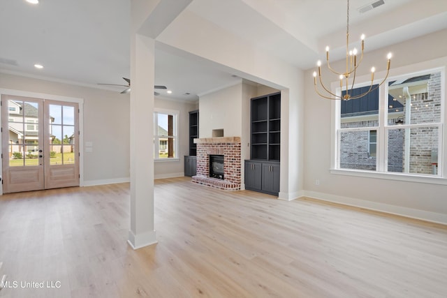 unfurnished living room with french doors, light hardwood / wood-style flooring, ornamental molding, a brick fireplace, and ceiling fan with notable chandelier