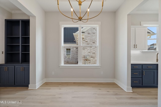 unfurnished dining area with crown molding, light hardwood / wood-style flooring, and a chandelier