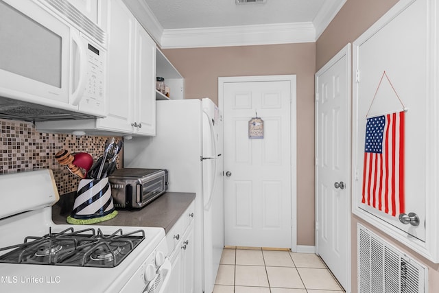 kitchen with ornamental molding, tasteful backsplash, light tile patterned floors, gas range, and white cabinets