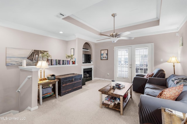 living room with ornamental molding, carpet, ceiling fan, and a raised ceiling