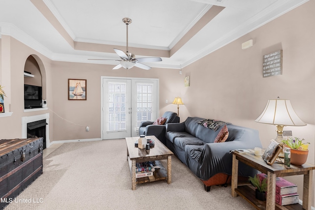 carpeted living room featuring ceiling fan, a raised ceiling, and crown molding