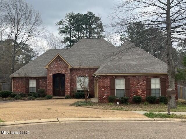 view of front of home with brick siding and a shingled roof